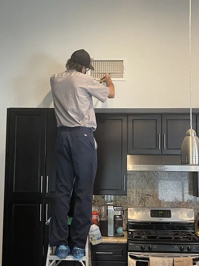 Technician inspecting an air vent during HVAC service in Cinco Ranch